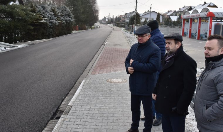 Cztery osoby po prawej stronie stoją obok nowej drogi, która jest po lewej stronie