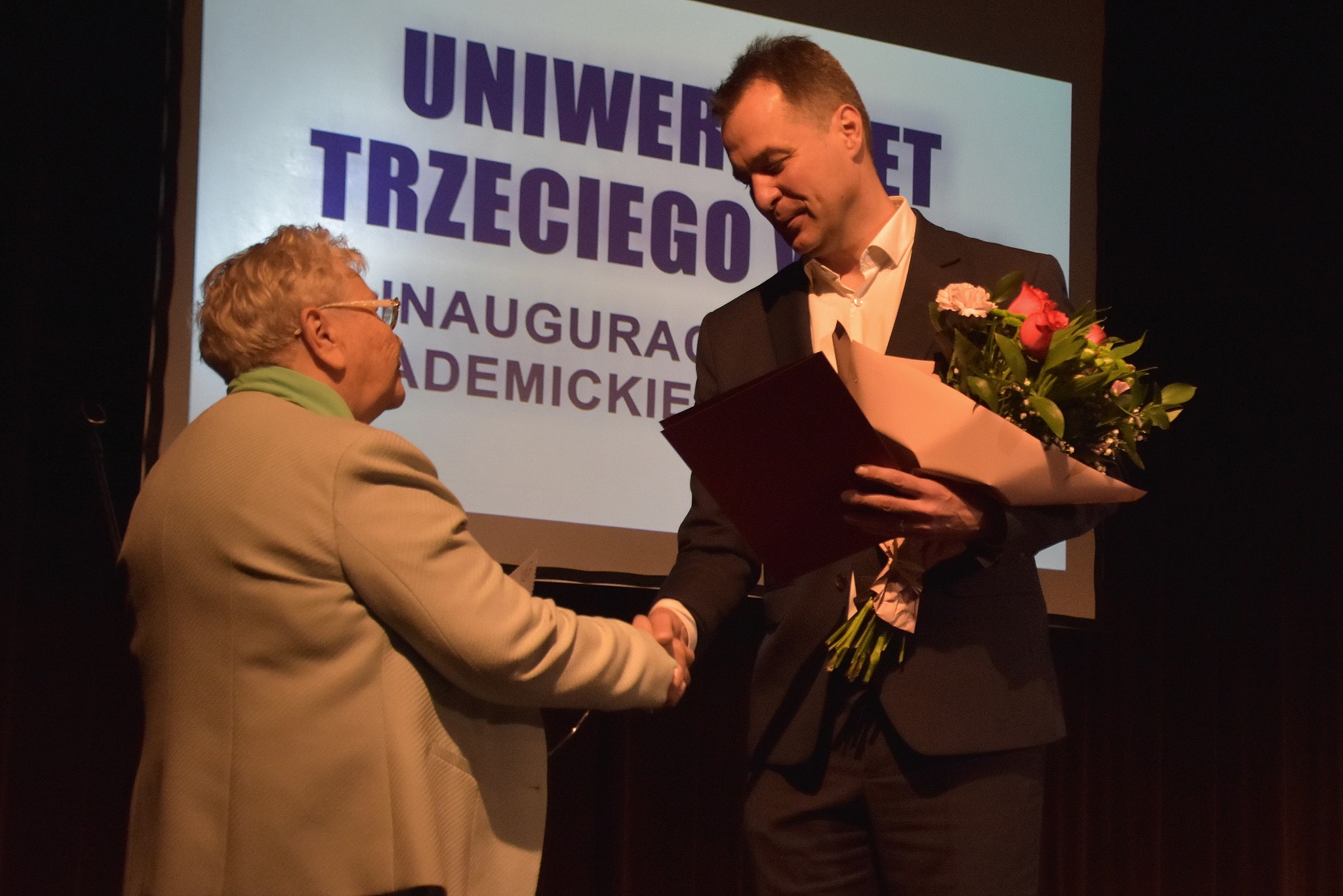 Starosta wręcza kwiaty koordynatorce UTW na scenie w OCK