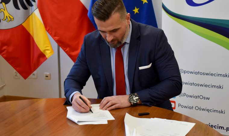 Mężczyzna w garniturze podpisujący dokument