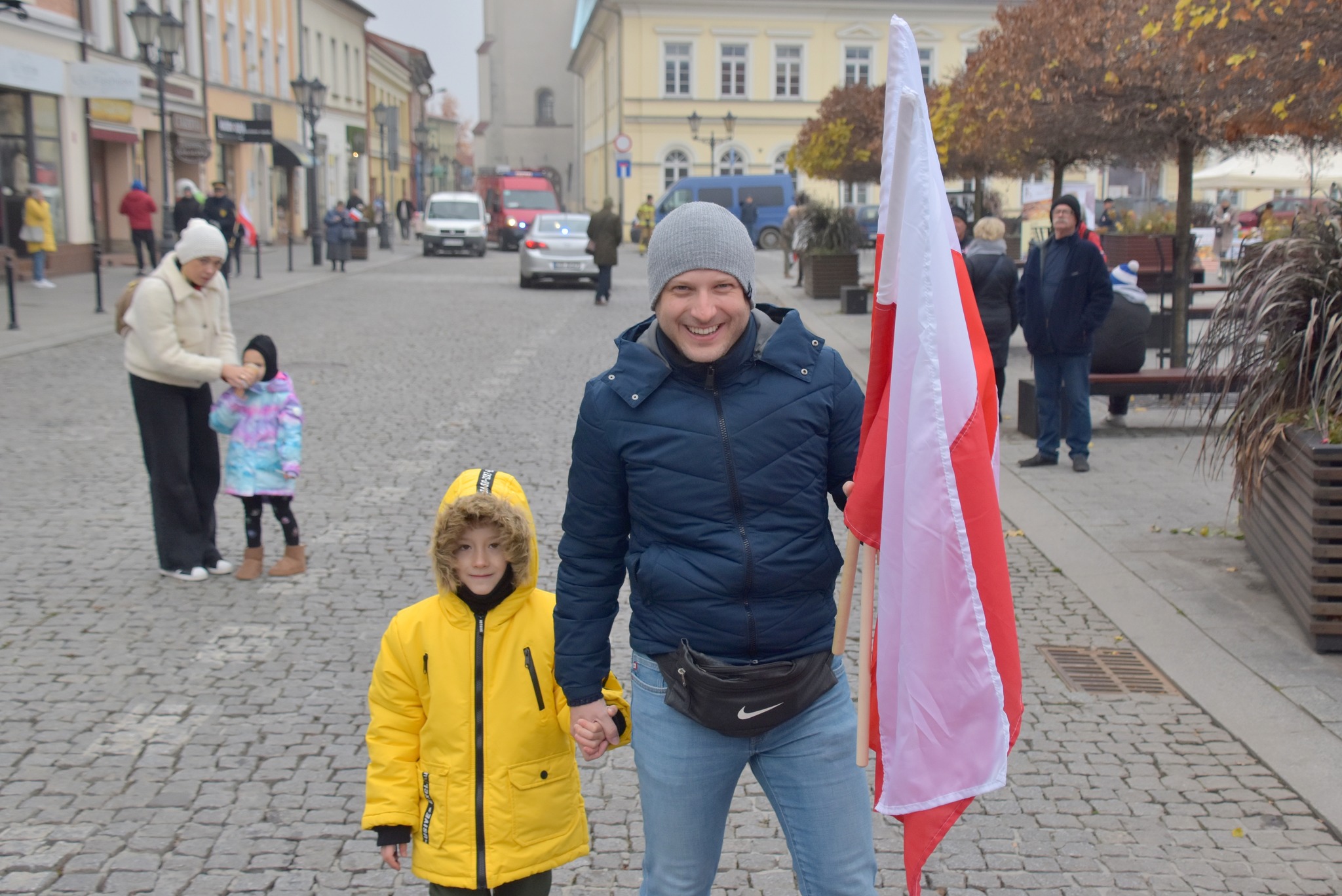 Ojciec i syn pozują na oświęcimskim Rynku do zdjęcia z biało-czerwoną flagą i uśmiechem na ustach