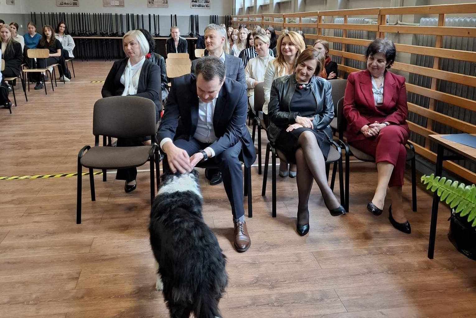 Starosta głaszczący psa podczas uroczystości w auli powiatowej Szóstki