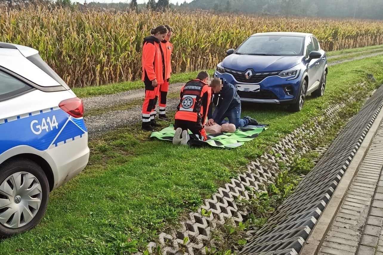 Kierowca auta wraz z ratownikiem ze szkoły wykonuje resuscytację na fantomie w terenie
