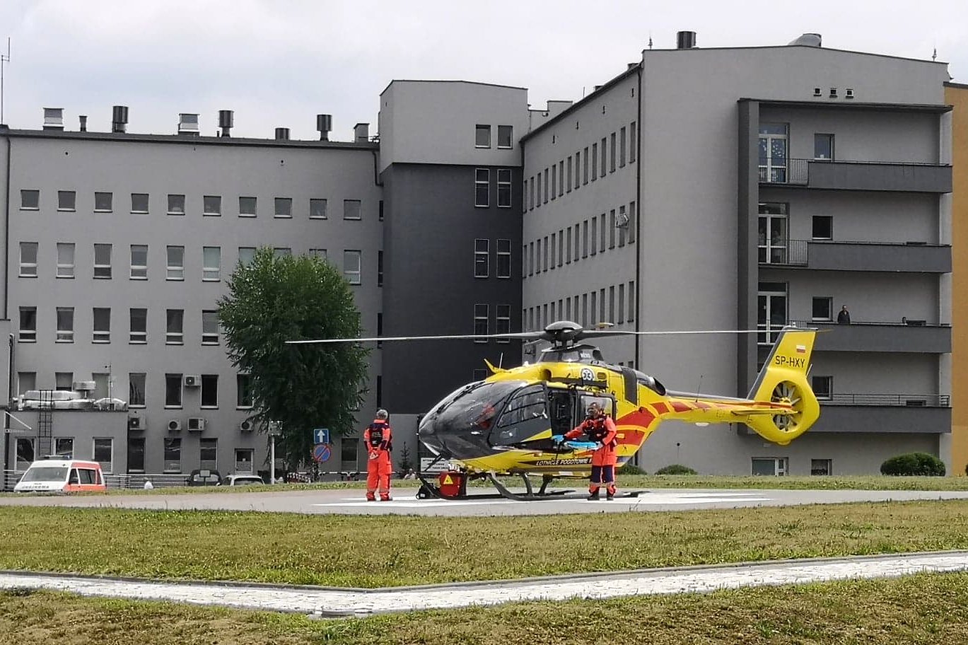 Widok na budynek główny Szpitala Powiatowego w Oświęcimiu. Na pierwszym planie helikopter medyczny i ratownicy.