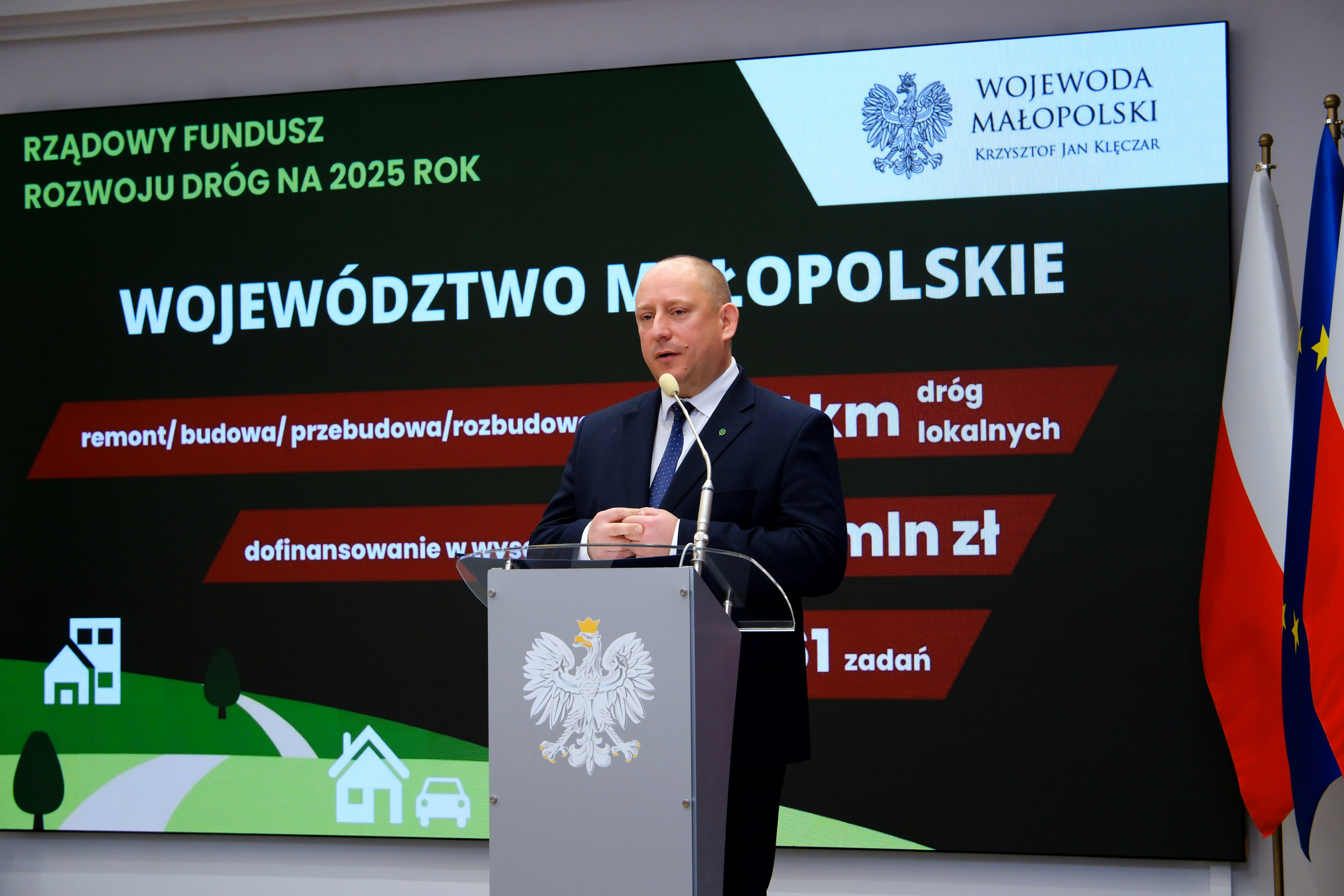Przemawia wojewoda małopolski. W tle grafika prezentująca dane o Rządowym Funduszowi Rozwoju Dróg