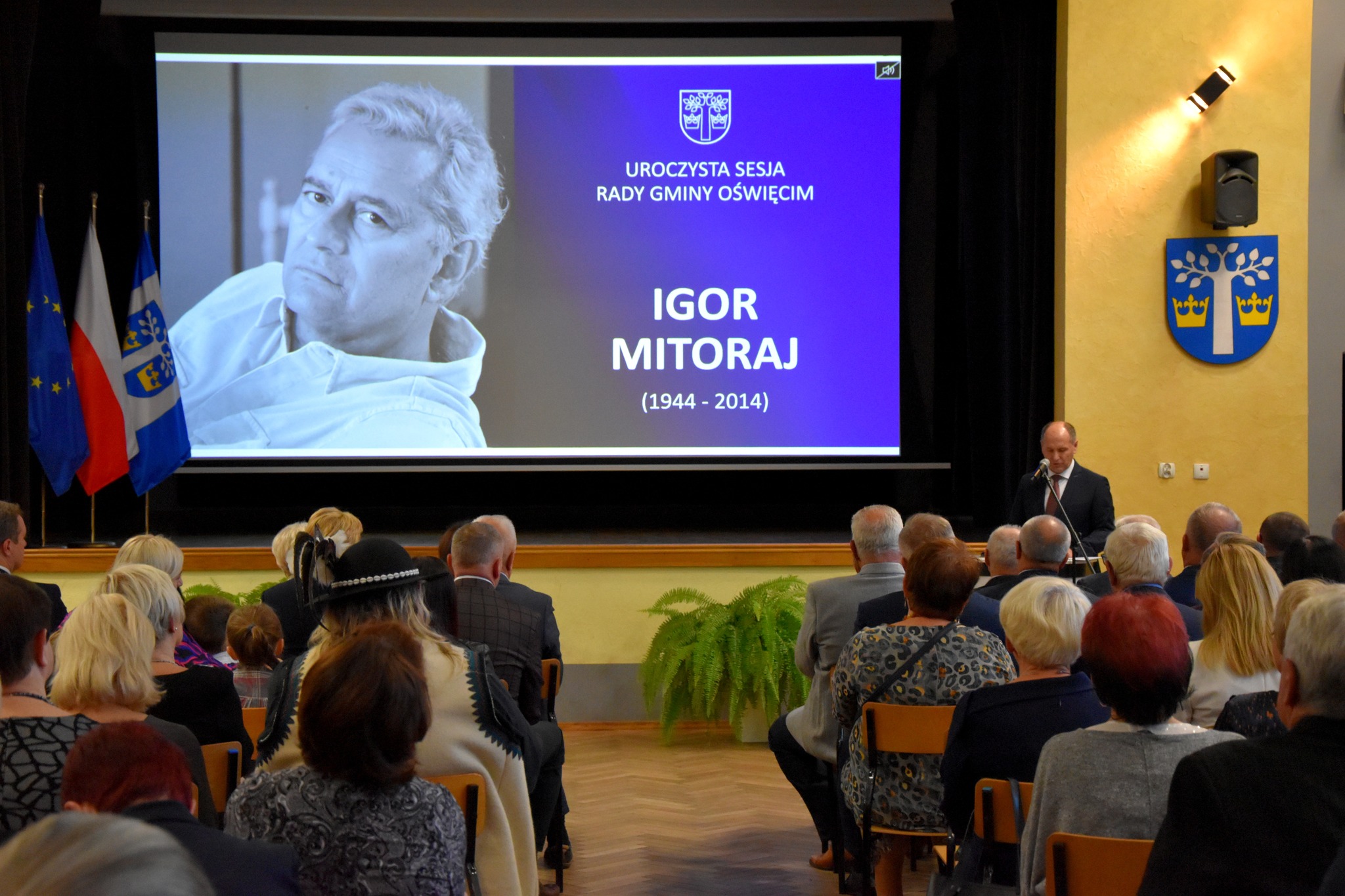 Widok na salę w Domu Ludowym w Grojcu, w której odbyła się uroczysta sesja Rady Gminy Oświęcim. W tle, na ekranie, postać Igora Mitoraja