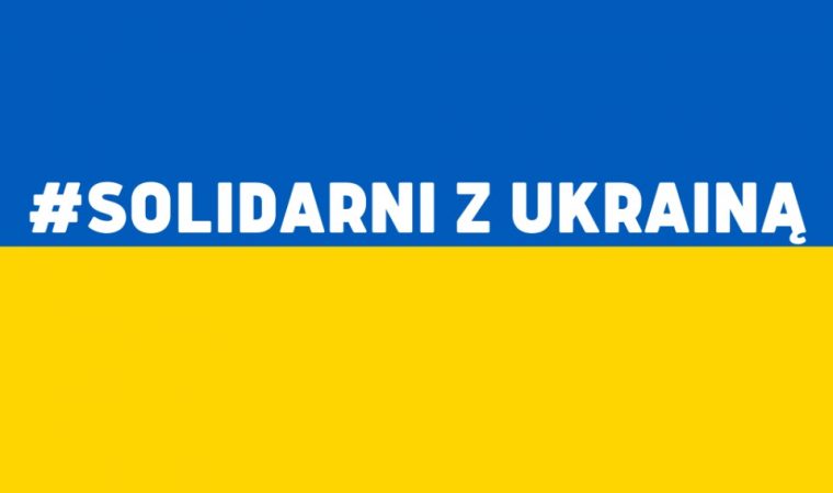 Flaga Ukrainy z napisem #SOLIDARNI Z UKRAINĄ na środku.