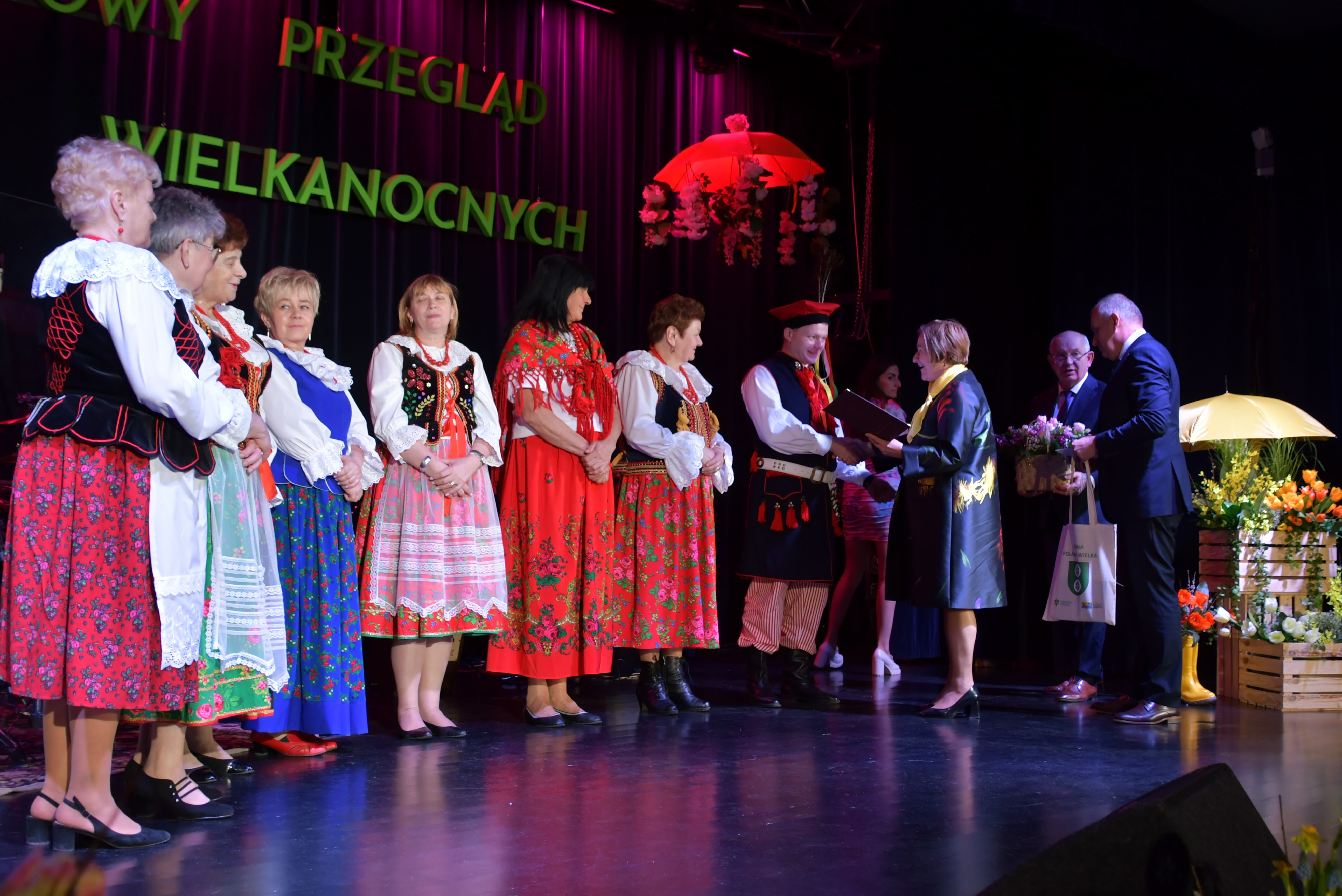 Na scenie ośrodka kultury pani wicestarosta wręcza bony przedstawicielom kół gospodyń i gospodarzy wiejskich