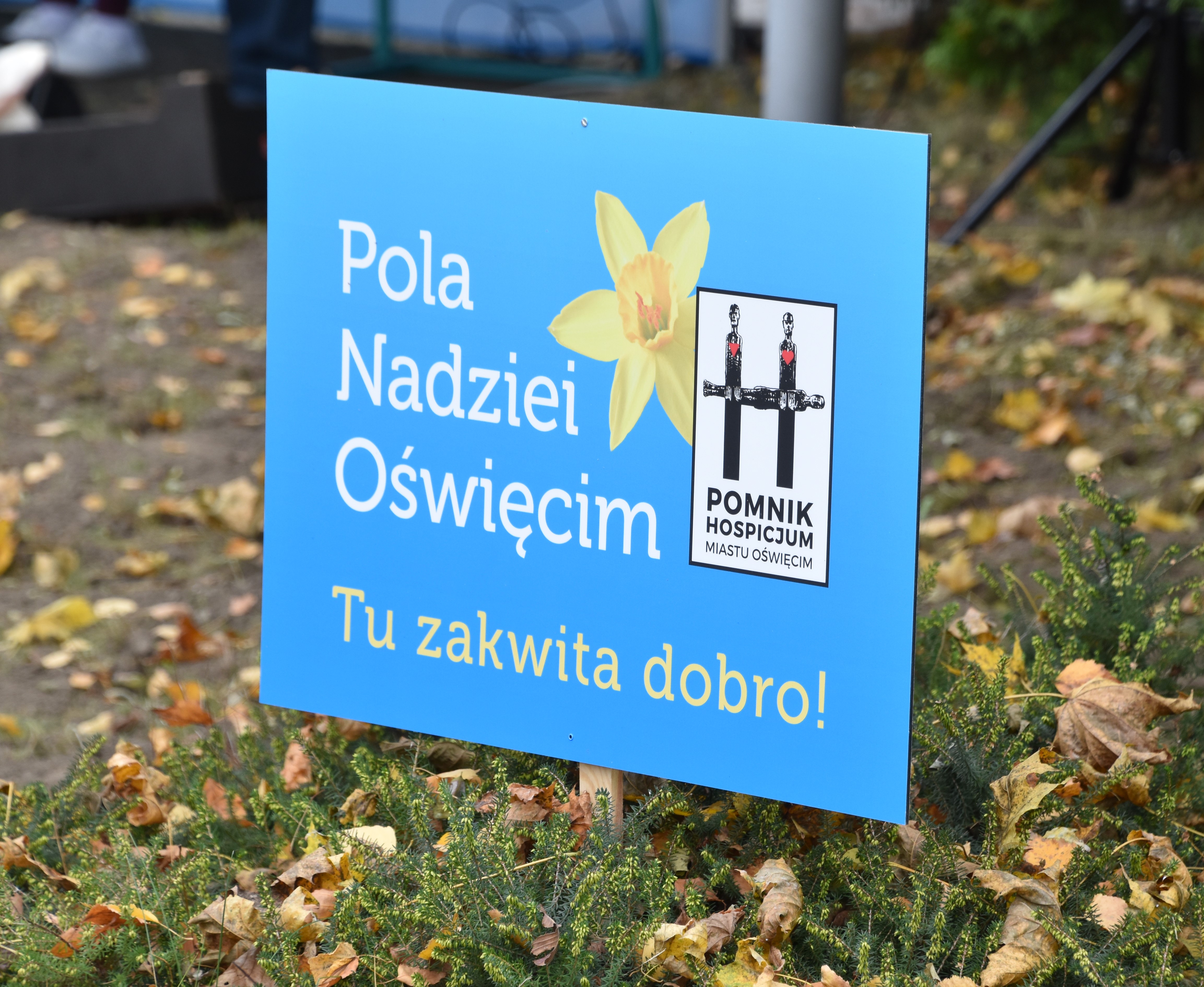 Tabliczka z napisem Pola Nadziei Oświęcim Tu zakwita dobro