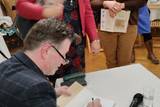 Autor podpisujący książkę o Księstwie Oświęcimskim.