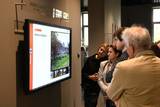 Goście, którzy przybyli do Muzeum Pamięci na inaugurację placówki wpatrują się w multimedialny ekran.