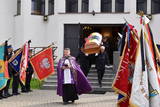 Kapłan wychodzący z kaplicy, za nim trumna niesiona przez czterech mężczyzn.