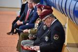 Siedzące osoby w granatowych mundurach i z bordowymi beretami na głowach 