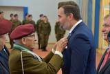 Starszy mężczyzna w mundurze po lewej stronie wręcza medal mężczyźnie po prawej stronie