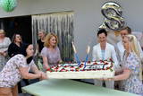 Urodzinowy tort wnoszą pracownice ośrodka