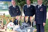 Strażacy stojący przy pucharach i medalach.