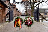 Wieńce od delegacji Powiatu Oświęcimskiego i Powiatu Dachau przez bramą z napisem Arbeit macht frei